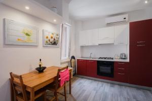 cocina con mesa de madera y armarios rojos en BED INN - Palazzo Urbe, en Olbia 28 fotos más