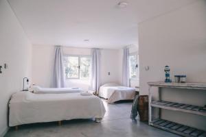 a white room with two beds and two windows at Benita Haus in La Estafeta +62 photos