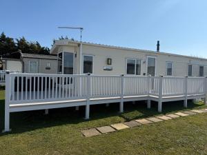 a white fence in front of a mobile home at Pebbles Romney Sands in Greatstone