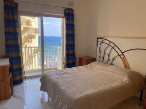 una camera da letto con un letto e vista sull'oceano di Horizon Apartments Gozo a Marsalforn