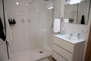 Un baño blanco con ducha y lavabo. en LA BALLENERA, en Cangas de Morrazo 26 fotos más