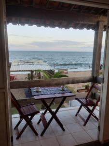 a table and chairs on a balcony with a view of the ocean at Pousada Capitão in Barra do Sirinhaém