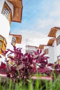 a group of buildings with purple flowers in the foreground at Hotel & Bungalows Villa Valencia in Huaraz