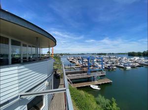 MaasbommelExclusive Houseboat La Mare 12 x 5 m in Maasbommel的码头,在水中停靠,靠近一座建筑