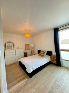 ein Schlafzimmer mit einem Bett und einem Kronleuchter in der Unterkunft Charmant appartement aux portes de Paris, avec Balcon et Parking in Aubervilliers