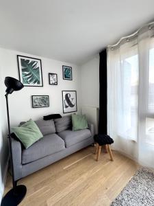 ein Wohnzimmer mit einer grauen Couch und einem Tisch in der Unterkunft Charmant appartement aux portes de Paris, avec Balcon et Parking in Aubervilliers