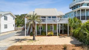 a house with a palm tree in front of it at Beach Retreat w Sundeck Golf Cart Bikes Bungalow House by AvantStay in Seacrest