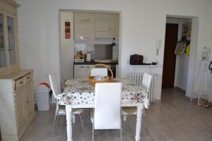 a kitchen with a table with white chairs and a table and a basket at Casa di Tea costa etrusca piombino in Piombino