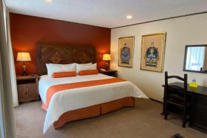 Un dormitorio con una cama grande con paredes naranjas. en Collection O Hotel La Huerta Golf & Hotel, Cholula, en Cholula