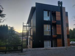 a black house with a staircase on the side of it at Viento azul in Villa La Angostura
