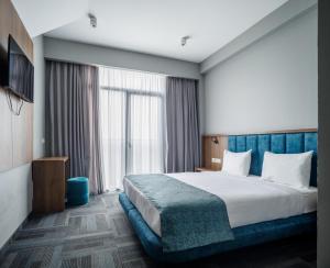 a bedroom with a large bed and a large window at Address Inn in Tbilisi City