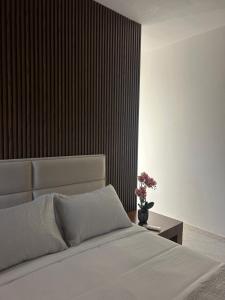a bedroom with a white bed and a table with flowers at Vila Kurti in Vlorë