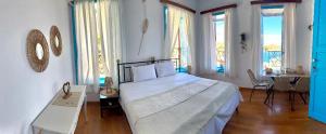 a bedroom with a bed and a table and windows at Maestro apartment Chalki in Halki