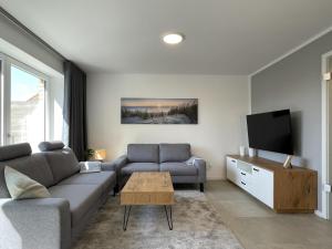a living room with a couch and a tv at Am Dahmer Leuchtturm 23f in Dahme