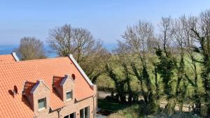 a house with an orange roof next to trees at Am Dahmer Leuchtturm 23f in Dahme
