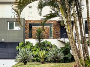ein Haus mit Palmen davor in der Unterkunft Luxo e segurança - 30 minutos de SP in Carapicuíba