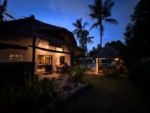 a house with a thatched roof at night at Kongo Dream in Diani Beach