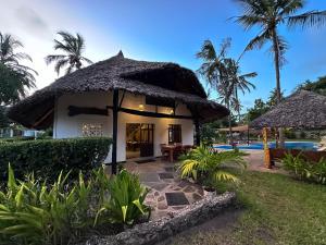 ディアニ・ビーチにあるKongo Dreamのスイミングプールのそばにわらぶき屋根のヴィラ