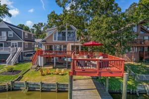 a house with a deck with a table and an umbrella at Waterfront Getaway - Dock UR Boat & Walk to Beach in Annapolis