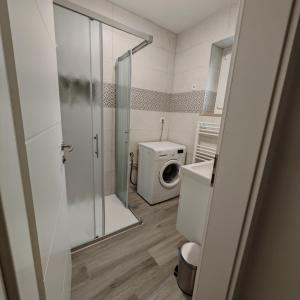 a bathroom with a shower and a washing machine at Apartment April in Bled