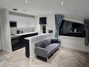 a living room with a chair and a kitchen at Lanark Apartment in Fort William