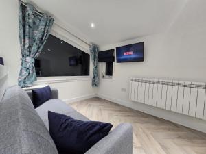 a living room with a couch and a flat screen tv at Lanark Apartment in Fort William