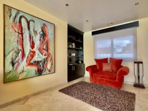 a living room with a red chair and a large painting at Oceanfront Villa 4BR 4 BA Real Mediterraneo in Tijuana