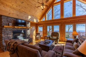 sala de estar con chimenea de piedra y TV en Cardinals View Lodge, en Blowing Rock