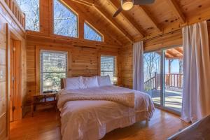 Un dormitorio con una cama en una cabaña de troncos en Cardinals View Lodge, en Blowing Rock