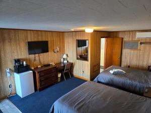 a hotel room with two beds and a desk and a television at Russell's Motel in Caribou