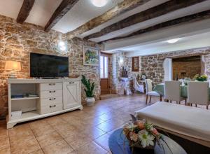 a living room with a tv and a stone wall at Haus Ana in Mali Ježenj