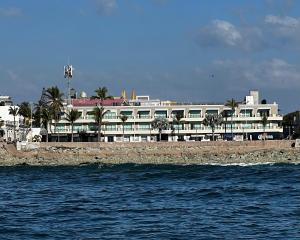 duży biały budynek z palmami nad wodą w obiekcie Hotel La Siesta Malecón w mieście Mazatlán