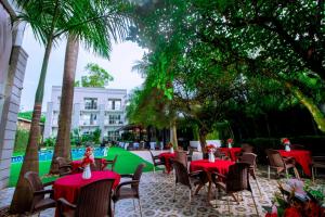 ジンジャにあるThe Mansion Hotel Jinjaの赤いテーブルとヤシの木のあるテーブルと椅子のグループ