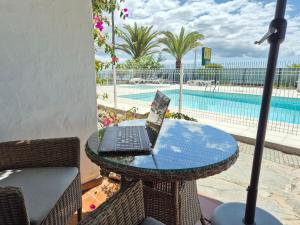 ein Laptop auf einem Tisch neben einem Pool in der Unterkunft 8i Ocean Front Playa 4 in San Bartolomé de Tirajana + 16 Fotos