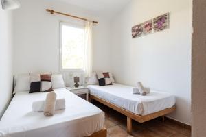 two beds in a room with white walls and a window at Villa Miguel in Cala en Bosc
