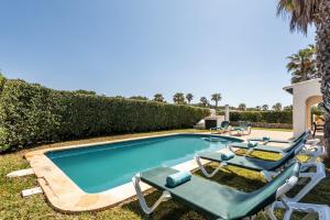 a swimming pool with two lounge chairs and a swimming pool at Villa Miguel in Cala en Bosc