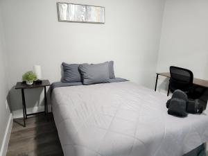 a bedroom with a white bed and a black chair at Homey 2br Home Near Dt & Airport in Austin