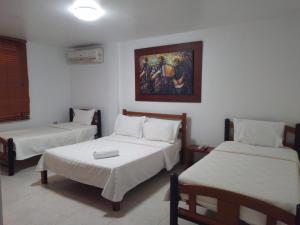 een kamer met twee bedden en een schilderij aan de muur bij Hotel La Casona Valledupar in Valledupar +17 foto's