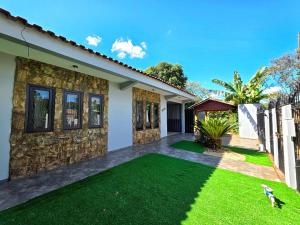 una casa con un prato verde davanti di Casa Quintal Amplo prox Cataratas 4 quartos a Foz do Iguaçu