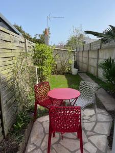 un patio con una mesa roja y 2 sillas en T3 St Malo- plage La Hoguette avec Jardin, en Saint-Malo