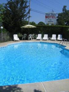 a large blue swimming pool with chairs and an umbrella at Twin Oaks Motel in Manasquan