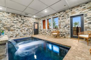 a swimming pool in a room with a stone wall at Indoor Pool Oasis, Hot Tub, EV, Scenic Views in Pigeon Forge