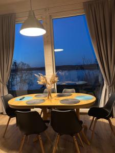 a dining room table with chairs and a large window at Sodyba Po klevu in Molėtai