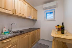 a kitchen with wooden cabinets and a sink and a counter at Vila Niko Dalmacija in Sukošan