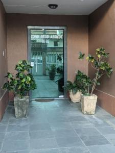 an entrance to a building with two potted plants at Apartamento charmoso in Rio das Ostras