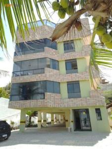 a building with a palm tree in front of it at Apto Praia do Meio in São-José-do-Ribamar
