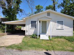 a small white house with a porch and a door at Sage Street Cottage in Winnsboro