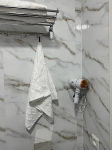 toalla blanca colgada de un toallero en el baño en Leon Hotel, en Taraz