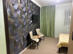 una habitación con dos sillas y una mesa y una cama en Leon Hotel, en Taraz