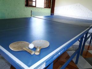 uma mesa de pingue-pongue com duas raquetes de pingue-pongue em Pousada das Acerolas em Penedo